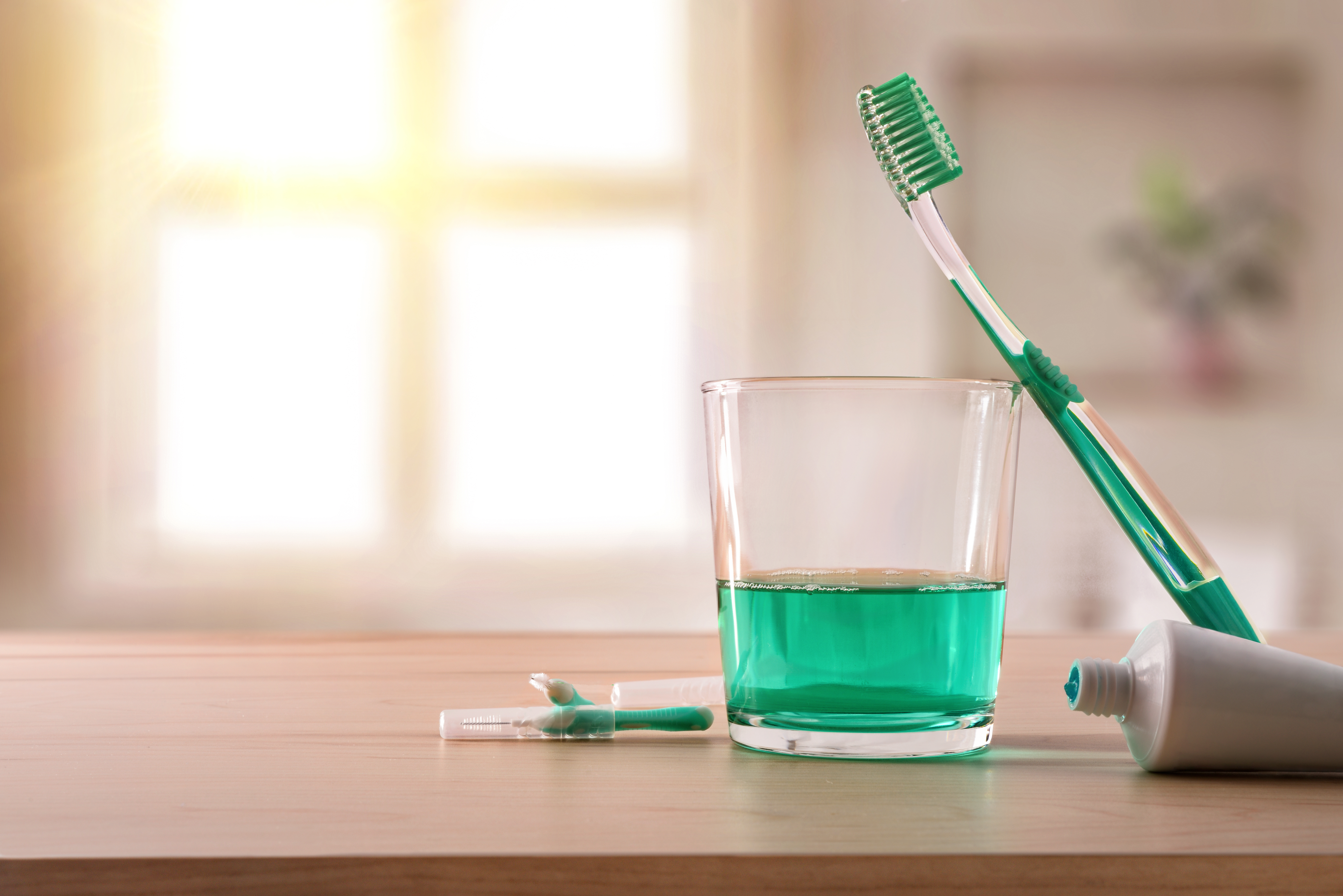 Glass of mouthwash with a toothbrush leaned against it