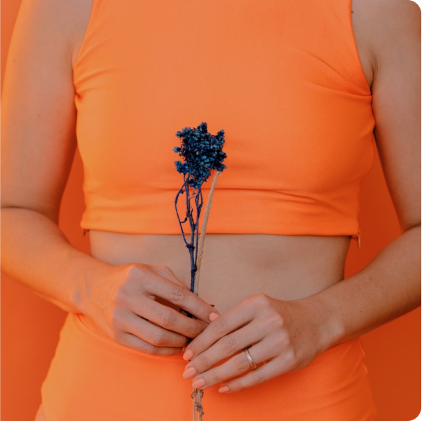 Woman holding flower in front of her torso