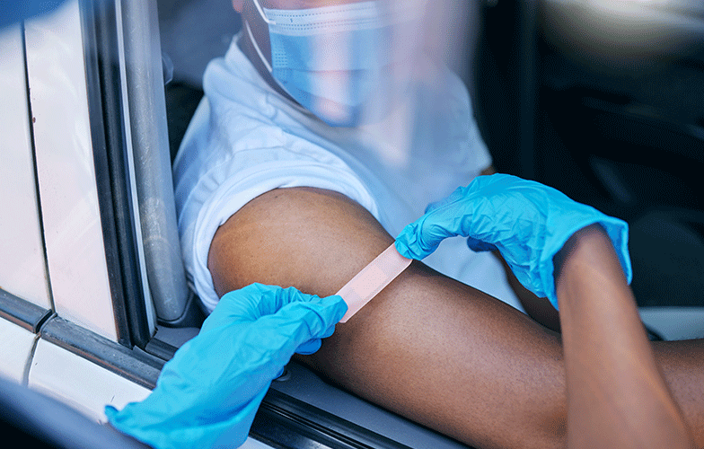 Close up of a person getting an adhesive bandage on arm while sitting in a car